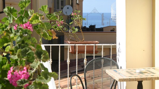 A balcony with a potted plant and a table with a chair. - Residenza Cardinale (Tropea)