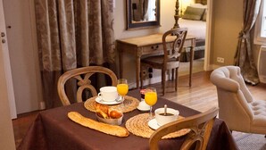 Un coin repas avec une table mise pour le petit-déjeuner, comprenant des croissants, une tasse de café et un verre de jus d’orange.
