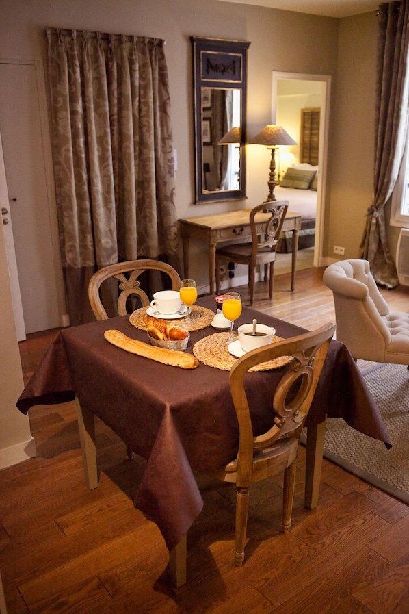 Un coin repas avec une table mise pour le petit-déjeuner, comprenant des croissants, une tasse de café et un verre de jus d’orange.