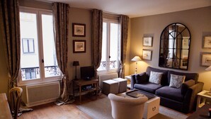 Un salon avec un canapé, un fauteuil, une télévision et un grand miroir.