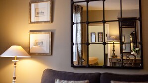 Une pièce avec un grand miroir, une lampe et des tableaux encadrés accrochés au mur.