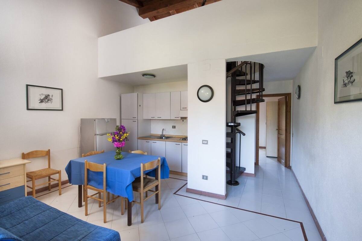 Eine kompakte Wohnung mit Essbereich, Küche und einer Treppe zu einer oberen Ebene.