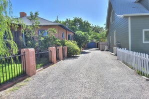 A residential street with houses on either side, a gravel driveway, and a white picket fence. - Old Town with private garden: quiet, spacious, CLEAN! (Albuquerque)