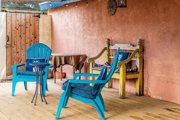 A patio area with two turquoise chairs and a small table, a wooden bench, and a rustic wall. - Old Town with private garden: quiet, spacious, CLEAN! (Albuquerque)