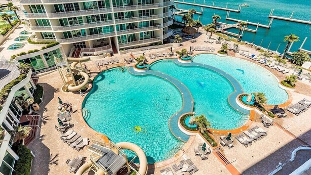 Un hotel con varias piscinas, un tobogán acuático y vistas al océano.