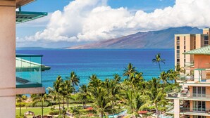 Un resort con vistas al océano y a las montañas, con palmeras y una zona de piscina.