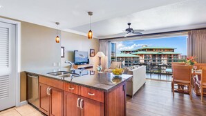 Una cocina moderna con una isla central, un comedor con vistas a un edificio y un balcón con mobiliario exterior.