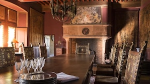 Un comedor con una larga mesa, sillas y una chimenea.