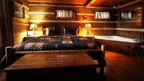 A wooden cabin room with a bed, two bedside lamps, a wooden table, and a bathtub. - SERENITY IN THE MOUNTAINS - Private-view-convenient-unique-hot tub-ev charging (Sevierville)