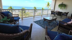 A balcony with wicker furniture, a glass table, and a view of the ocean. - Beachfront Oasis~ Huge Terrace ~ Amazing Sunsets~ Resort Pool~ Grill~ Beach gear (Jacó)