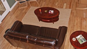 A living room with a stone fireplace, leather sofa, wooden coffee table, and a television.
