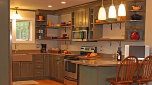 A modern kitchen with wooden cabinets, a central island, and bar stools.