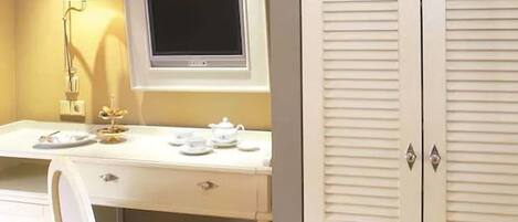 A room with a desk, a chair, a television, and a wardrobe.