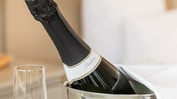 Una botella de champán en un cubo metálico con una copa a un lado.