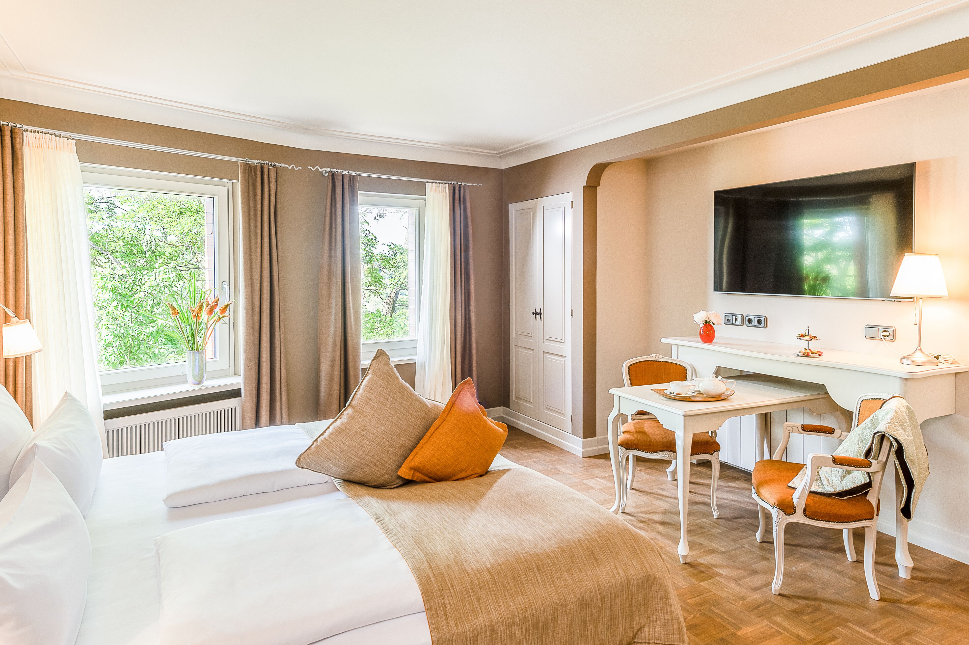 A hotel room with a bed, a desk, a chair, a TV, and a window with curtains.