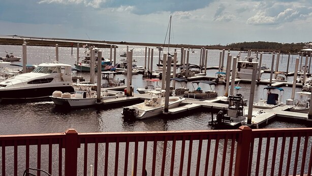 A marina with boats docked, a wooden deck, and metal chairs.