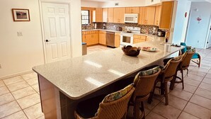 A spacious kitchen with a large island, wooden cabinets, a microwave, and a dishwasher.
