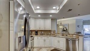 Una cucina moderna con mobili bianchi, elettrodomestici in acciaio inossidabile e pavimento piastrellato.