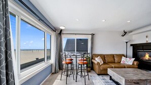 A modern living room with a large window, a fireplace, a sofa, and a coffee table.
