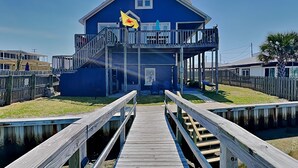 Een blauw huis met een balkon, een houten steiger en een vlag.