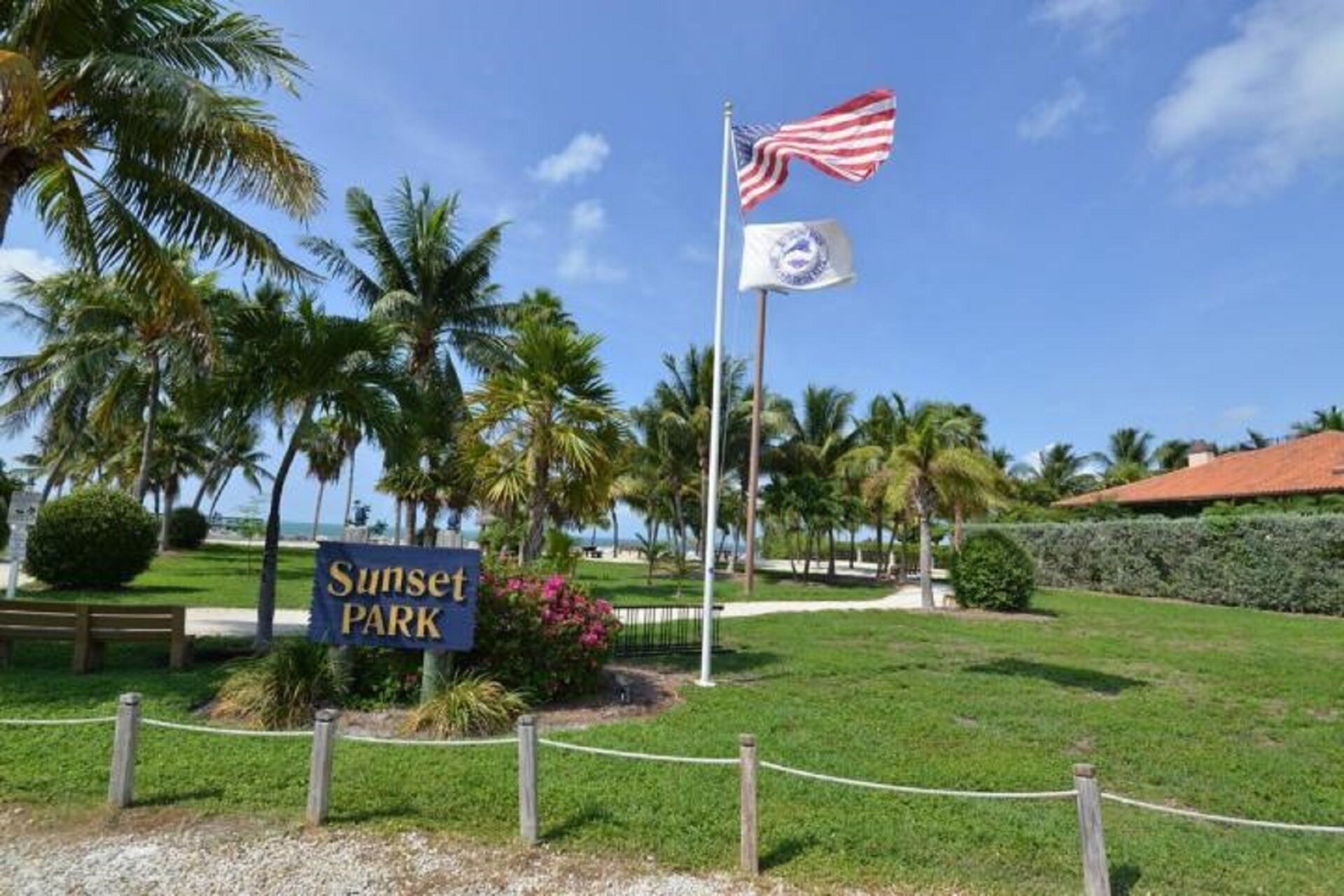 A sign for Sunset Park with an American flag and a state flag.