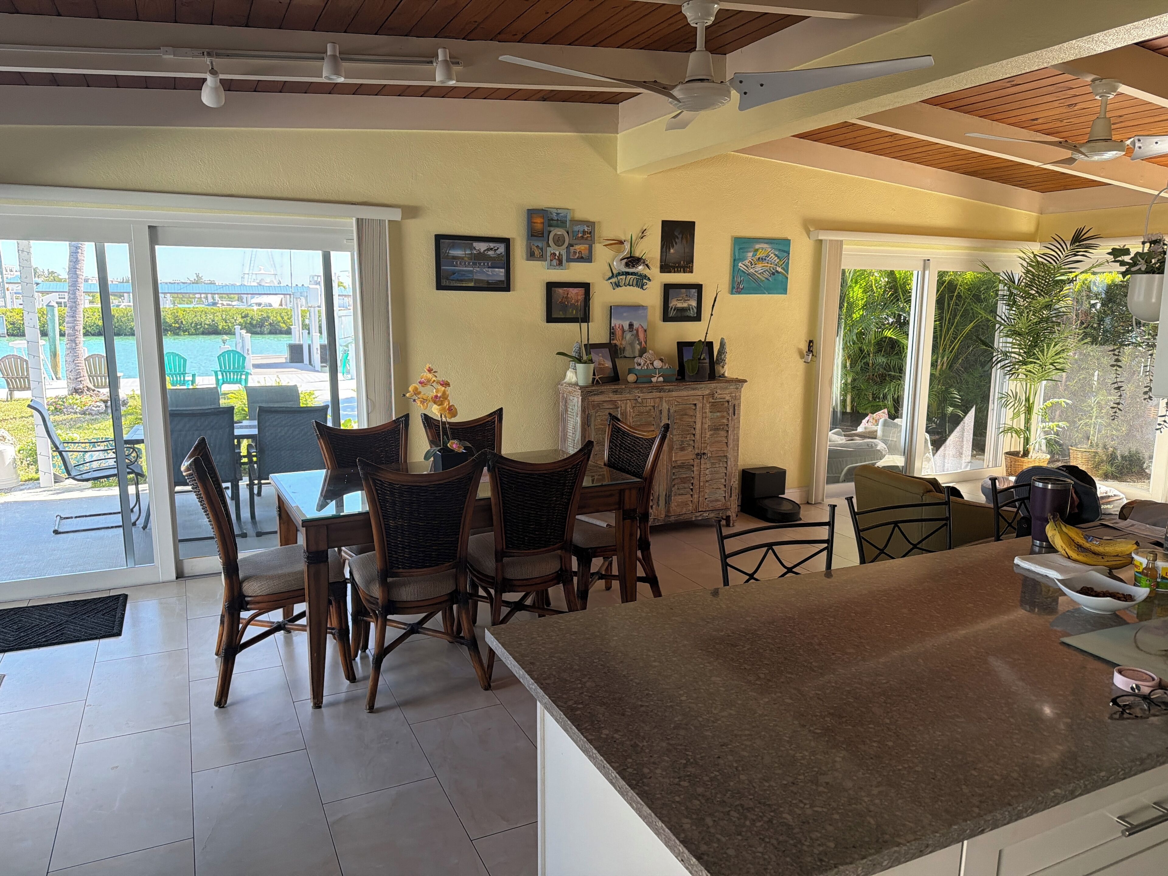 A dining area with a table and chairs, a cabinet with decorative items, and a view of the outdoors.