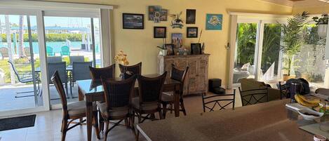 A dining area with a table and chairs, a cabinet with decorative items, and a view of the outdoors.