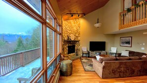 A cozy living room with a stone fireplace, a large TV, and a comfortable sofa. - V3 Gorgeous Ski-In slopeside Townhouse with Amazing Mountain Views in Bretton Woods. Dog Friendly! (Bretton Woods)