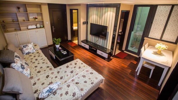 A modern bedroom with a bed, a TV, a small table, and a wardrobe. - Zixinju Aparthotel (Changsha)