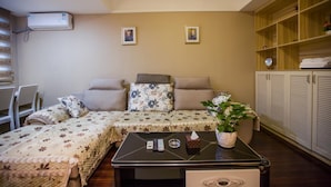 A bedroom with a sofa bed, a bedside table with a plant, and a wardrobe with louvered doors. - Zixinju Aparthotel (Changsha)
