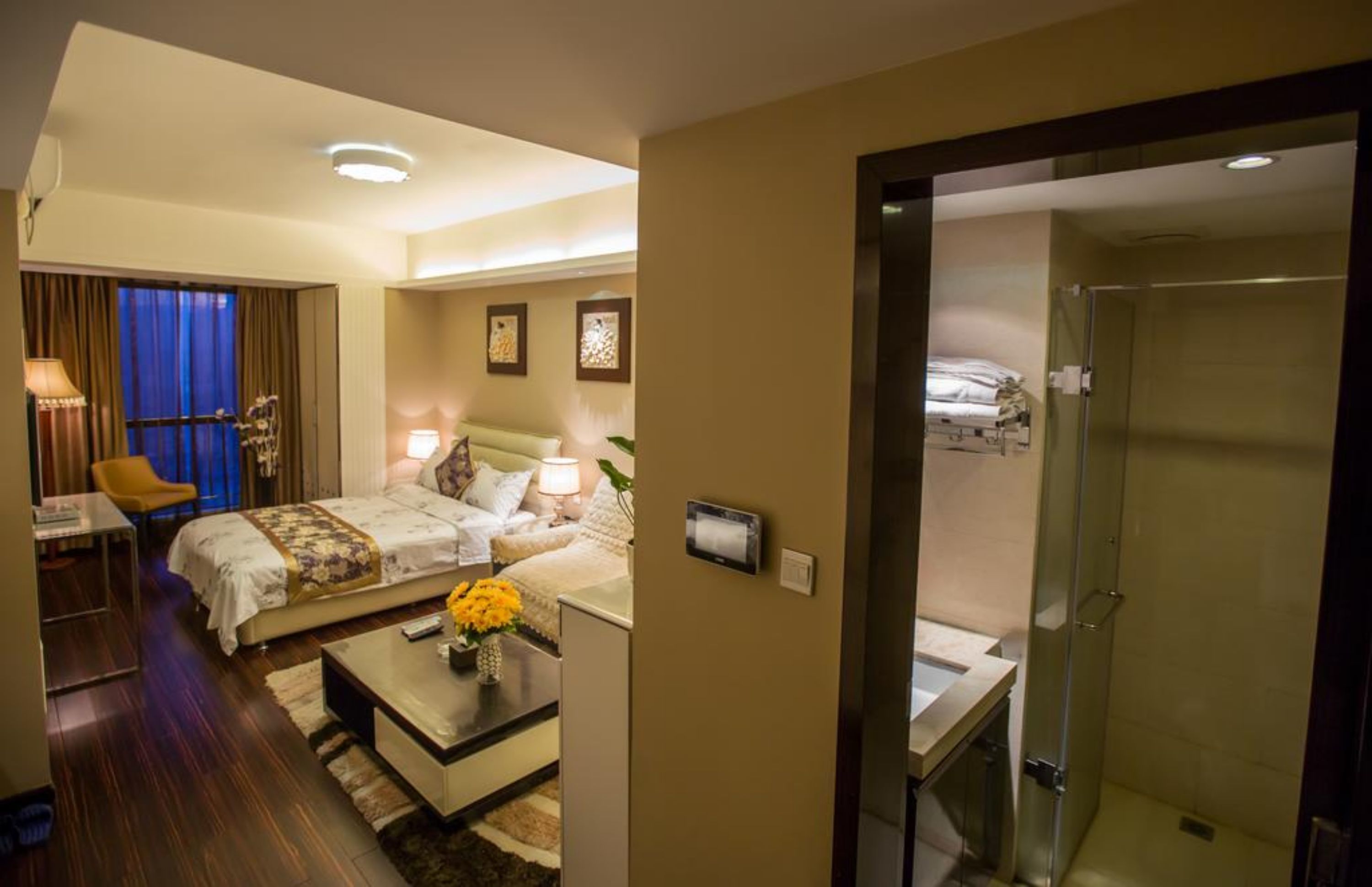 A hotel room with a bed, bedside table, lamp, and a small seating area with a chair and table.