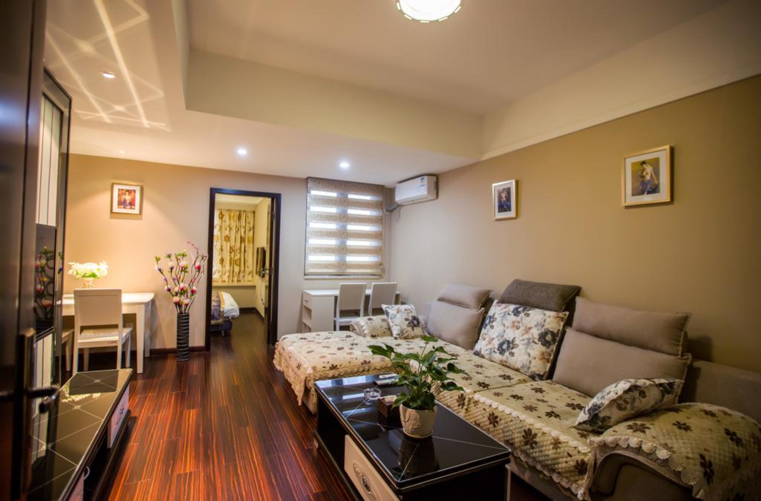 A well-lit, modern living room with a sofa, a coffee table, and a dining area with a table and chairs.