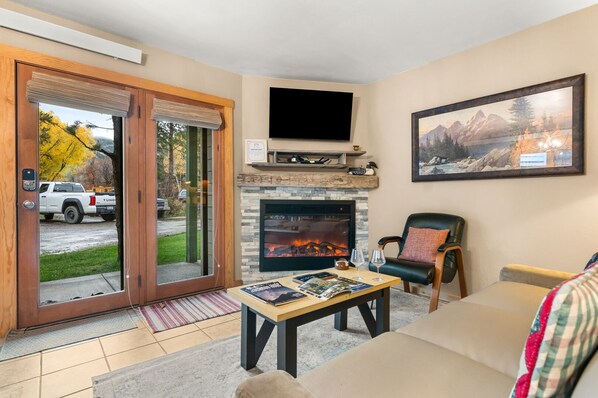 A living room with a fireplace, a television mounted above it, and a large painting on the wall.
