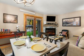 A dining area with a fireplace, a television mounted above it, and a painting on the wall.