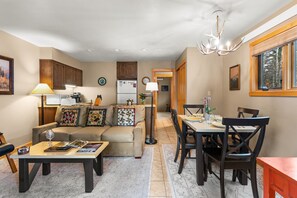A cozy living room with a sofa, coffee table, and dining area with chairs and a table.