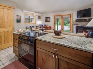 Une cuisine équipée d’une cuisinière intégrée, de meubles en bois et d’une cheminée en pierre.