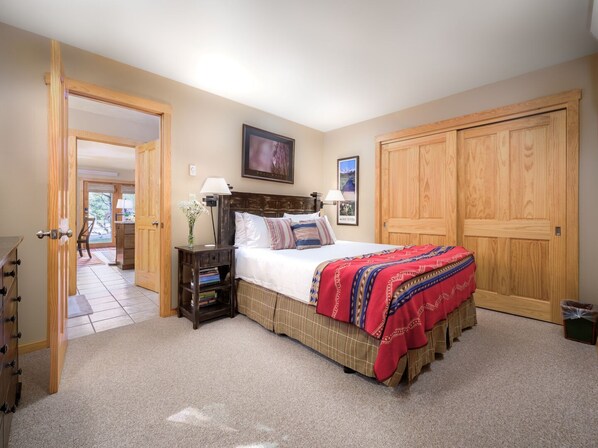 Une chambre à coucher avec un lit, des tables de chevet, une lampe, un cadre photo et une armoire.