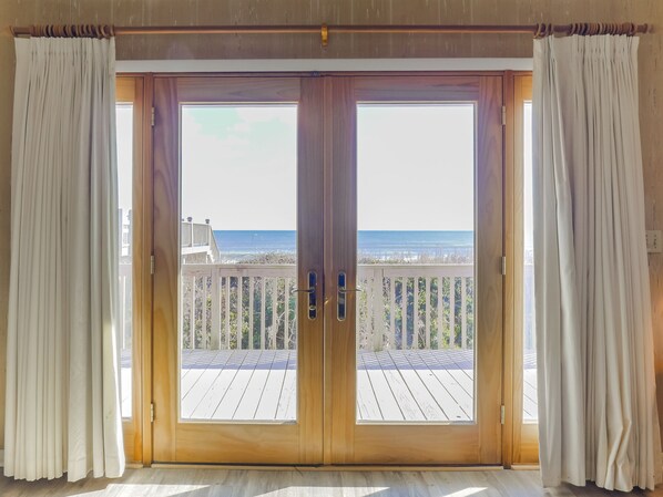 Een kamer met een grote glazen schuifdeur die uitkomt op een balkon met uitzicht op de oceaan.