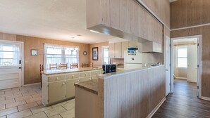 Une cuisine avec des meubles en bois, un îlot central et une fenêtre avec des rideaux.
