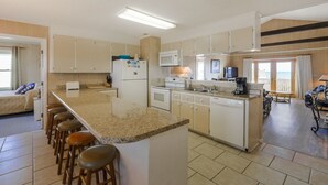 Une cuisine spacieuse dotée d’un îlot central, un coin repas offrant une vue agréable et un espace de vie séparé.