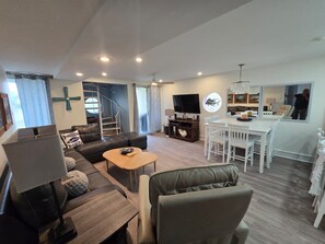 A modern living room with a sofa, coffee table, TV, and a dining area with a table and chairs.