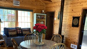 L’intérieur chaleureux d’un chalet comprend une table à manger, des chaises, une bibliothèque et une enseigne indiquant le nom du chalet.