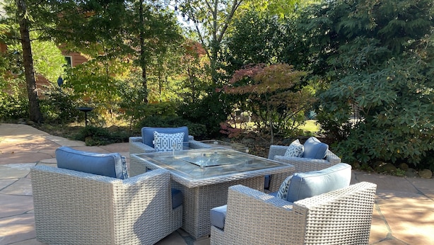 Une terrasse dotée de meubles en osier et d’une table à plateau en verre.