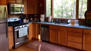 Une cuisine rustique, située dans une cabane en bois, équipée d’une cuisinière, d’un four à micro-ondes et d’un évier.