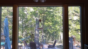 Une pièce dotée de grandes fenêtres donnant sur une terrasse aménagée avec des meubles d’extérieur et une statue.