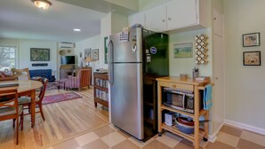 A modern kitchen with a stainless steel refrigerator, wooden cabinets, a microwave, and a dining area with a table and chairs. - Living Color - Updated, Private Mid-Century in a Quiet, Convenient Neighborhood! (Hood River)