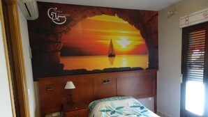 A bedroom with a bed, a nightstand, a lamp, a wall mural of a sunset over water, and a window with blinds. - Hostal Gonzalez (Guadarrama)