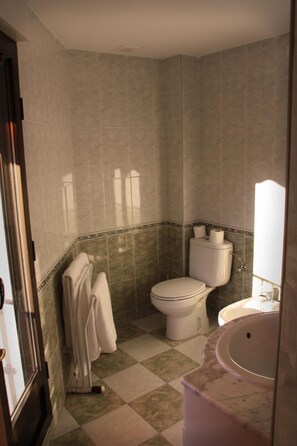 A bathroom with a toilet, sink, and towel rack. - Hostal Gonzalez (Guadarrama)