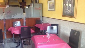 A restaurant interior with tables covered in red tablecloths, chairs, and wine glasses. - Hostal Gonzalez (Guadarrama)