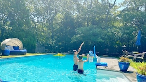 Ein Schwimmbecken mit einem blauen Luftmatratze, einer überdachten Sitzgelegenheit und einer Terrasse mit Gartenmöbeln.